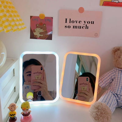 Stylish desktop LED vanity mirrors in pastel colors on a table, perfect for makeup and decoration.