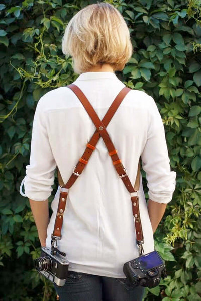 Stylish leather camera strap on a person, perfect for travel, featuring a pin buckle design in rich brown.