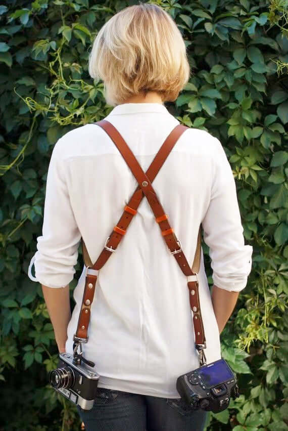 Stylish leather camera strap harness for travel, designed for comfort and functionality with dual camera support.