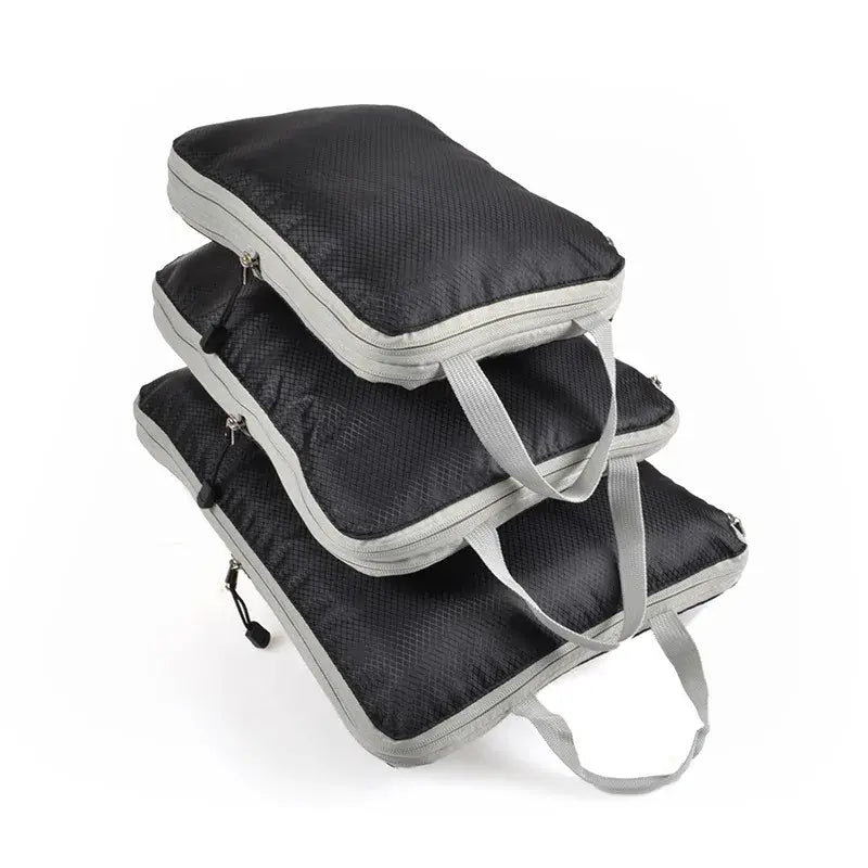 Three foldable and compressible packing cubes in black with gray handles, ideal for travel storage and organization.