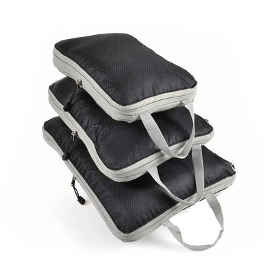 Three foldable and compressible packing cubes in black with gray handles, ideal for travel storage and organization.