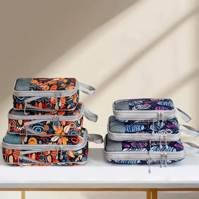 Set of 4 colorful compression storage bags on a table, featuring patterns and zip closures for organized packing.