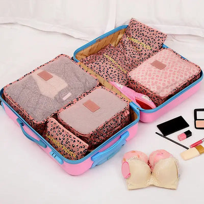 Open suitcase filled with colorful packing cubes for organized travel, including pouches for clothing and lingerie.