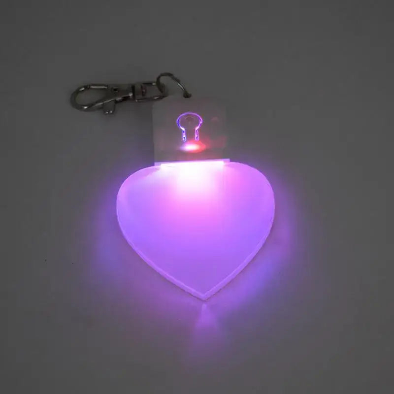Heart-shaped LED light keychain emitting purple glow, perfect for handbags and night use.