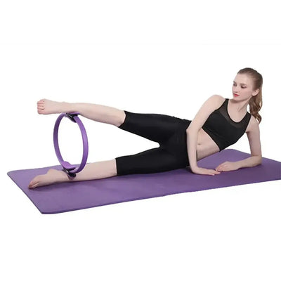 Woman performing leg exercises with a purple Pilates ring on a yoga mat, showcasing beginner fitness training.