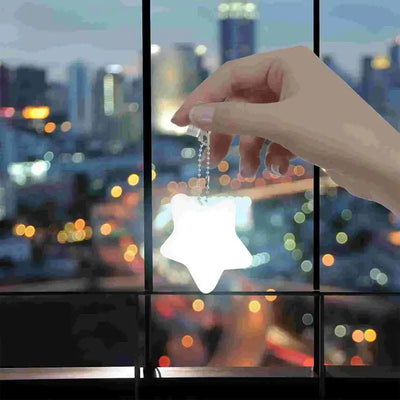 Hand holding a star-shaped LED handbag light with a chain, glowing softly against a blurred city skyline at night.
