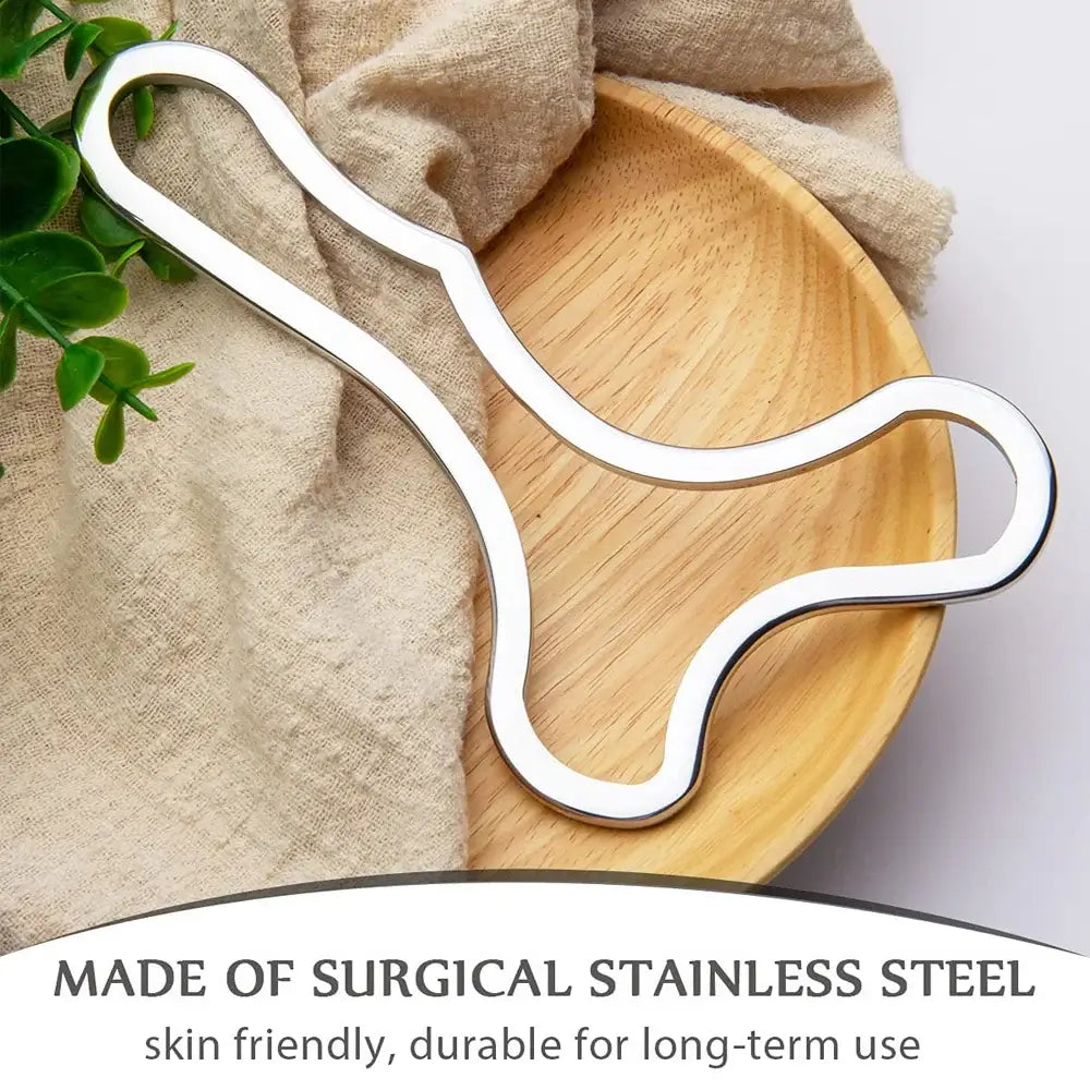 Stainless steel Gua Sha scraping tool on a wooden plate, designed for muscle relief and lymphatic drainage.