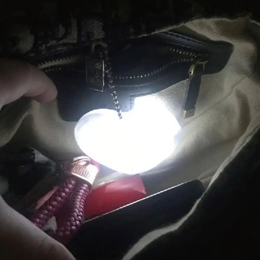 LED heart-shaped light illuminating a handbag interior, showcasing convenient purse accessory for women.