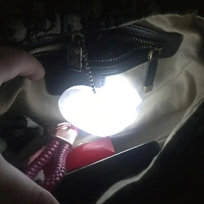 LED heart-shaped light illuminating a handbag interior, showcasing convenient purse accessory for women.