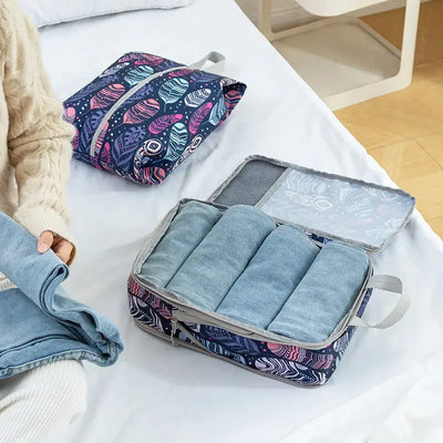 Person folding jeans next to colorful compression storage bags for travel organization.