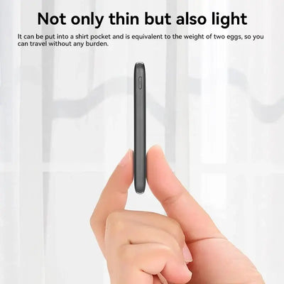 Slim and lightweight power bank held between fingers, ideal for easy portability in a shirt pocket.