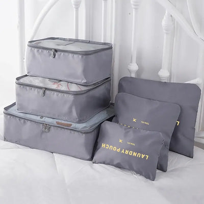 Set of gray travel packing cubes and pouches, perfect for organizing clothes and accessories during travel.