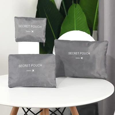 3 sizes of grey travel pouches labeled 'Secret Pouch' on a table, perfect for organizing luggage.