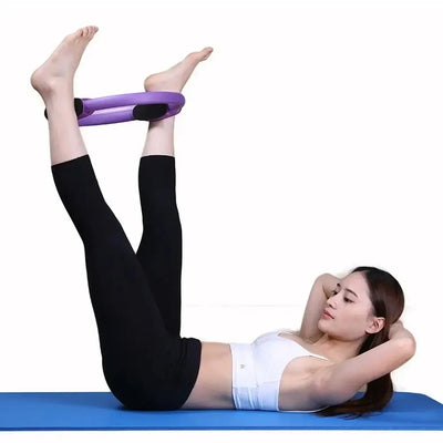 Woman using a purple Pilates ring for leg exercises on a yoga mat, promoting fitness and body shaping.