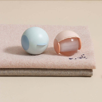 Spherical hair sticking device in blue and peach colors on a soft fabric background, perfect for travel and hair dyeing.