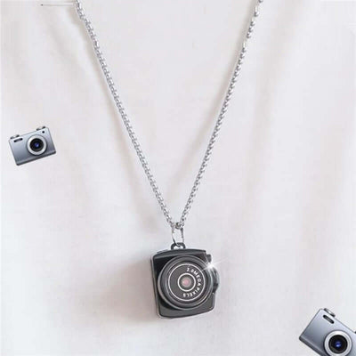 Black camera necklace pendant on silver chain, stylish accessory for photography lovers.