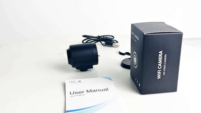 Smart wireless WiFi home security surveillance camera with user manual and packaging on a white background.