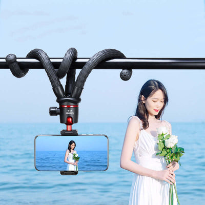 Camera Desktop Live Handheld Vlog Stand with octopus bracket, supporting a smartphone by the beach.